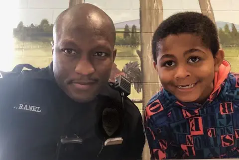 A police officer and his son posing for the camera.